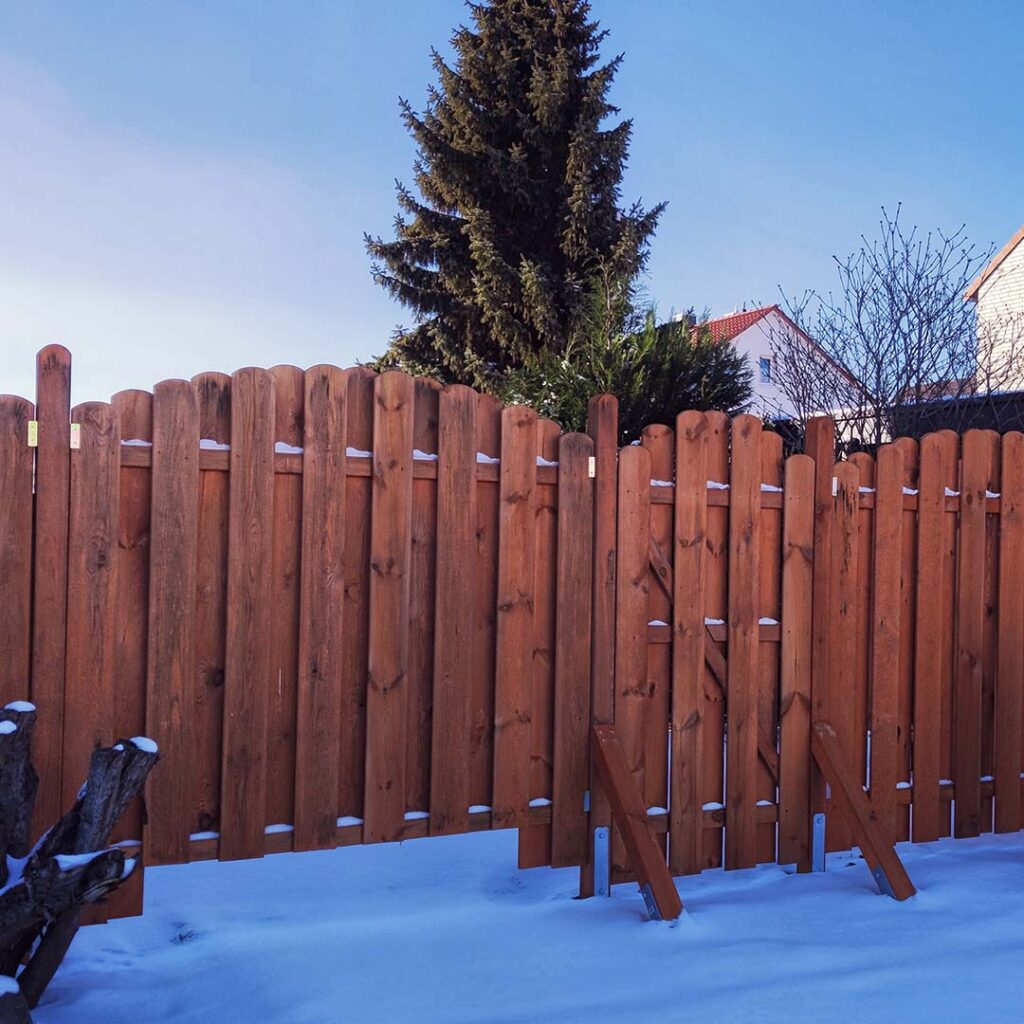 wooden fence in snowy backyard