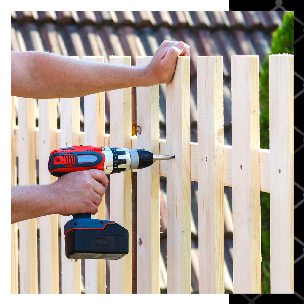 man drilling screw into new built picket fence